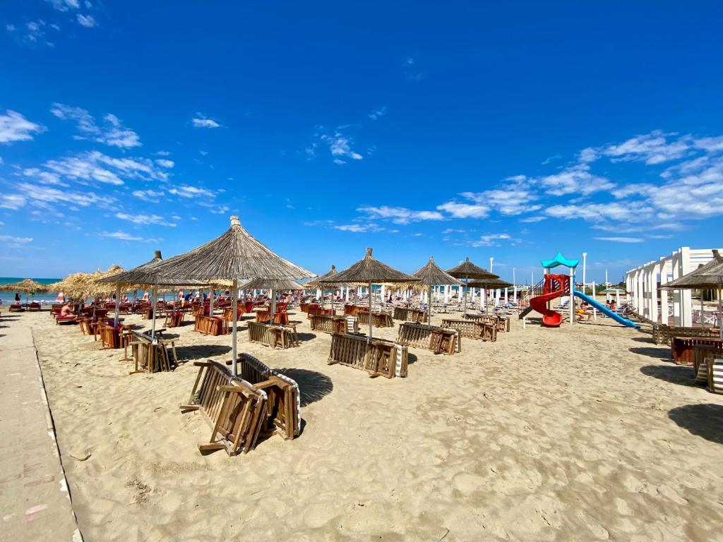 une plage avec des chaises et des parasols ainsi qu'une aire de jeux dans l'établissement Durres, Plazh 13, Albania, à Durrës