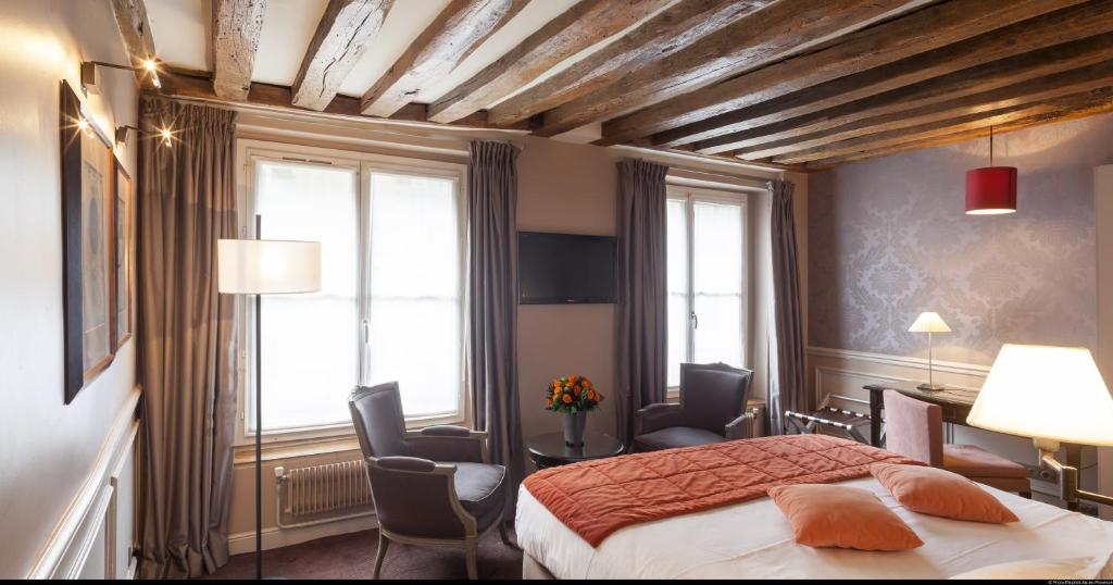 um quarto com uma cama e cadeiras num quarto em Hotel de L'Universite em Paris