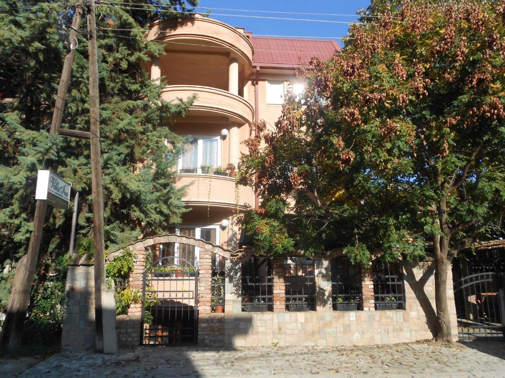 um edifício com uma cerca em frente a uma árvore em Villa Iva em Skopje