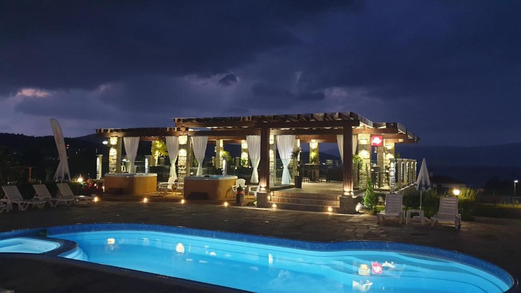 a swimming pool in front of a gazebo at night at Family Hotel Eterno in Tsigov Chark