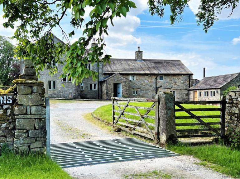 una vieja casa de piedra con una puerta y una valla en Swans Farm, en Lancaster