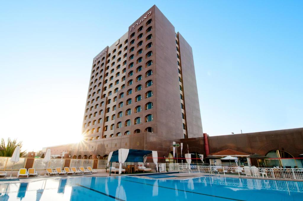 un hotel con piscina frente a un edificio en Leonardo Hotel Negev en Beer Sheva