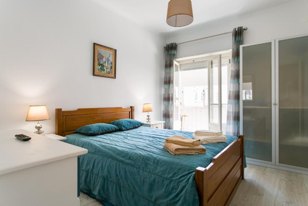 Schlafzimmer mit einem Bett mit blauer Bettwäsche und blauen Kissen in der Unterkunft Isabel Dream IV in Algueirão-Mem Martins