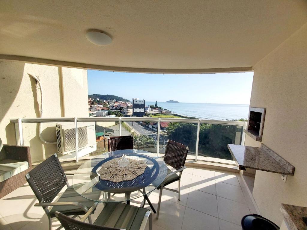 d'un balcon avec une table et des chaises et une vue sur l'océan. dans l'établissement Espetacular vista do mar - Beto Carrero - Ap502, à Penha