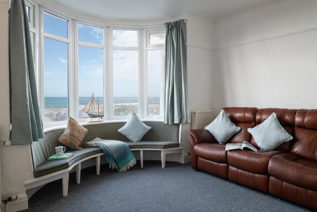 a living room with a couch and a large window at Beachcliffe House - Sea front property - Sleeps 10 - Pet friendly in Llandrillo-yn-Rhôs