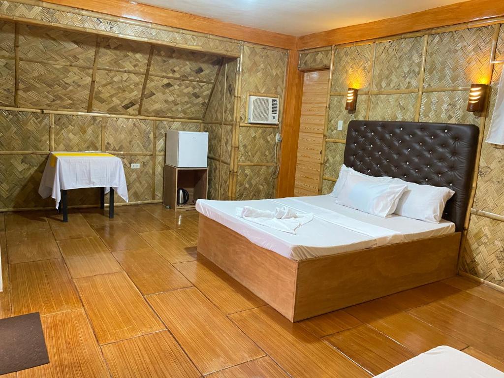 a bedroom with a bed in a room with a table at Don Roberto's Kubo Resort in Nasugbu