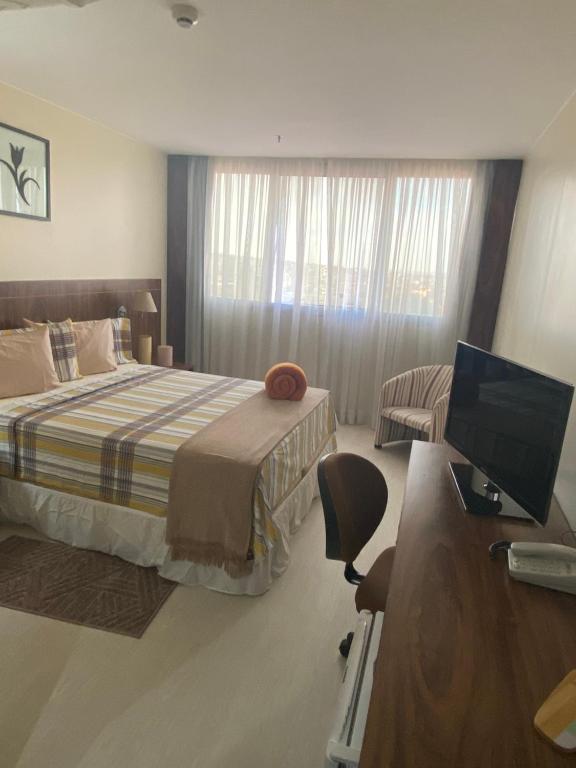 Schlafzimmer mit einem Bett und einem Schreibtisch mit einem Computer in der Unterkunft Flat encantador com piscina e área de lazer in Brasilia