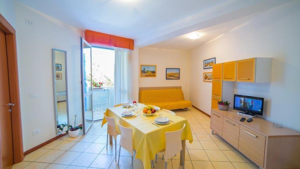 sala de estar con mesa y sofá amarillo en Aparthotel Gioia, en Caorle