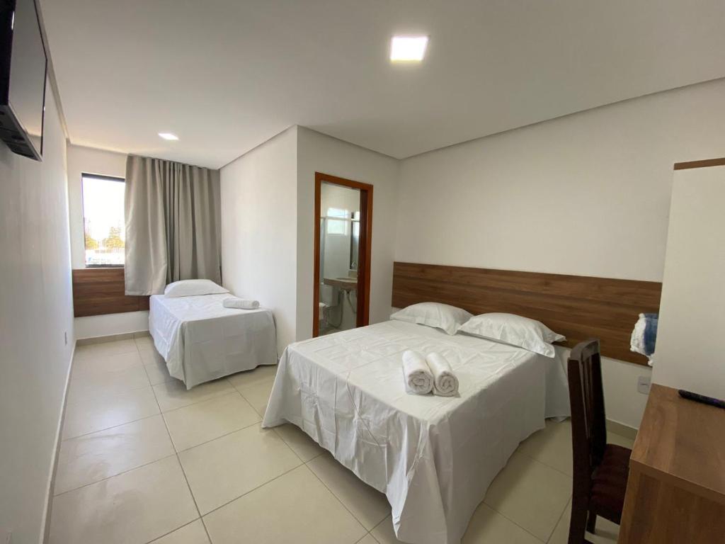 um quarto de hotel com duas camas e uma janela em Hotel Vitória em Vitória da Conquista