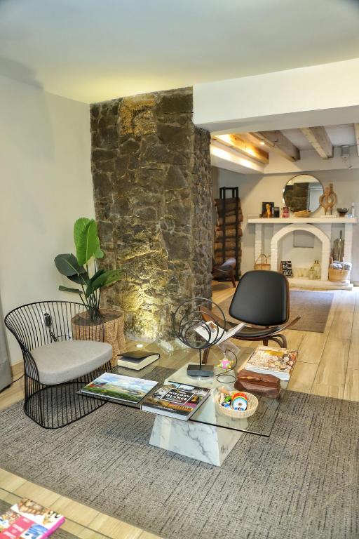A lounge corner framed by a stone column, with a fireplace and open kitchen area behind it.