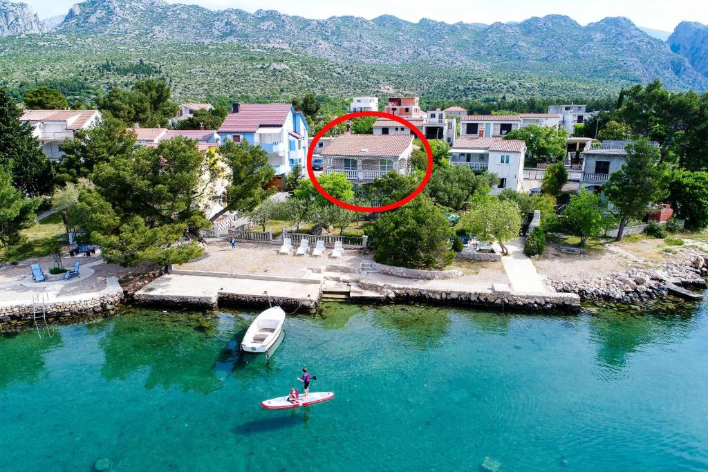 une personne sur une planche de surf dans l'eau près d'une maison dans l'établissement Apartments by the sea Seline, Paklenica - 6531, à Starigrad-Paklenica