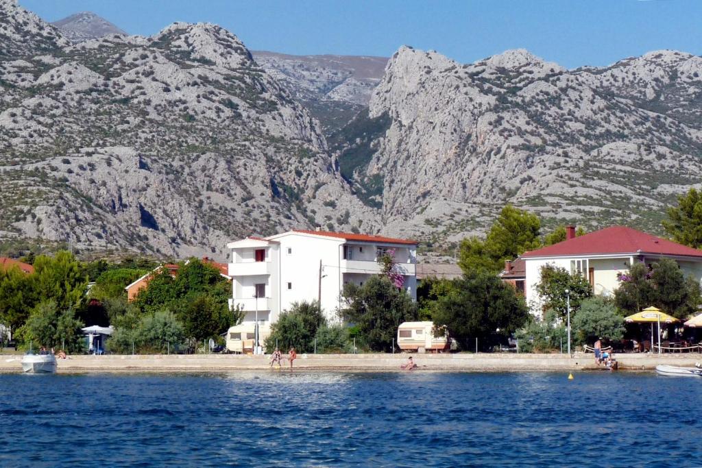a group of people on a beach with mountains in the background at Apartments and rooms by the sea Seline, Paklenica - 6440 in Starigrad-Paklenica