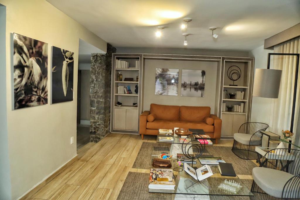 A wider view of the hotel lounge with an orange sofa, lounge chairs and bookshelves.