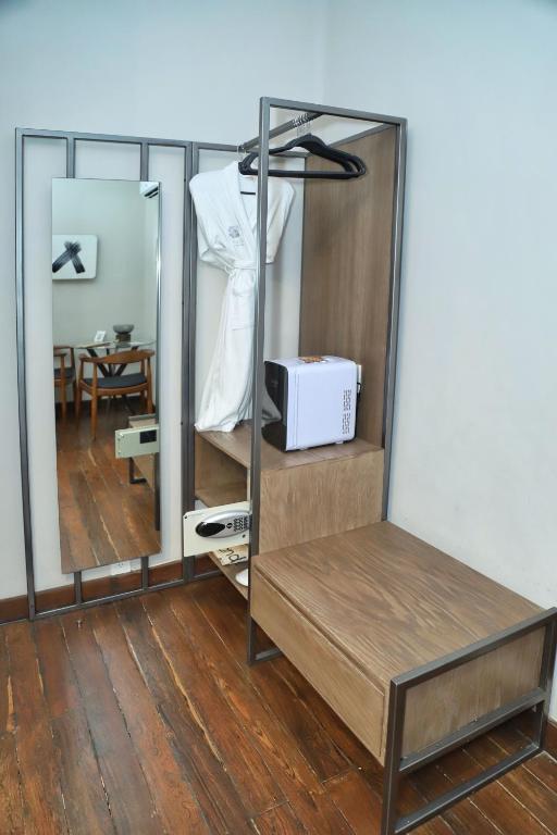 A compact room workspace beside open wardrobe storage, with a mirror and in-room amenities.