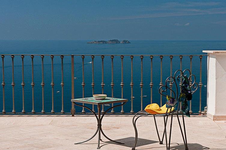 een tafel en stoelen op een balkon met uitzicht op de oceaan bij Villa Rosa in Positano