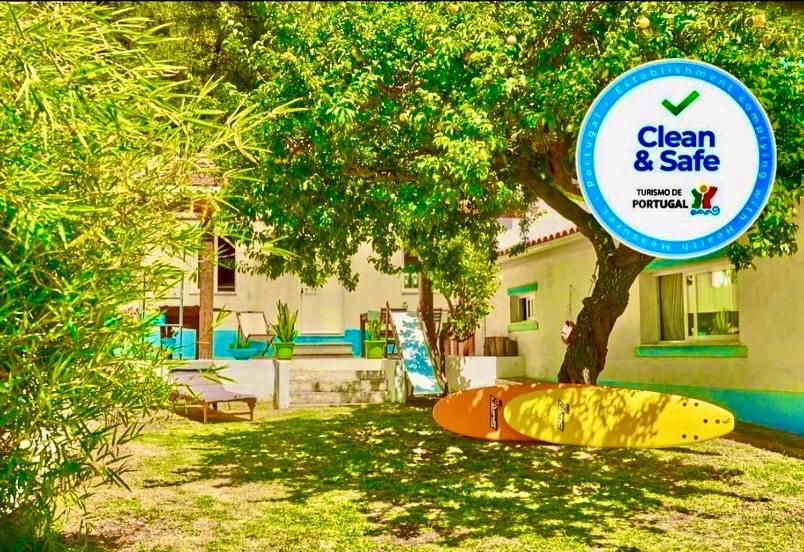 コスタ・ダ・カパリカにあるA Perfect Vacation - Beach and Cityの家の隣の木の下に座るサーフボード