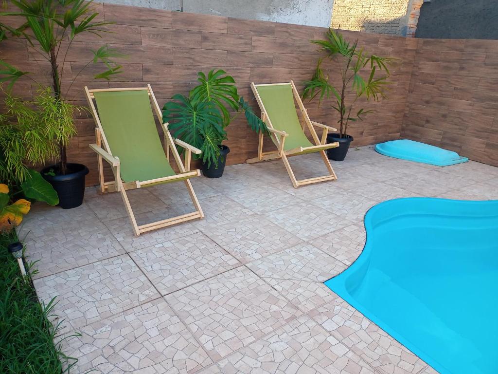 twee ligstoelen op een patio met planten bij Casa para temporada Florianópolis in Florianópolis