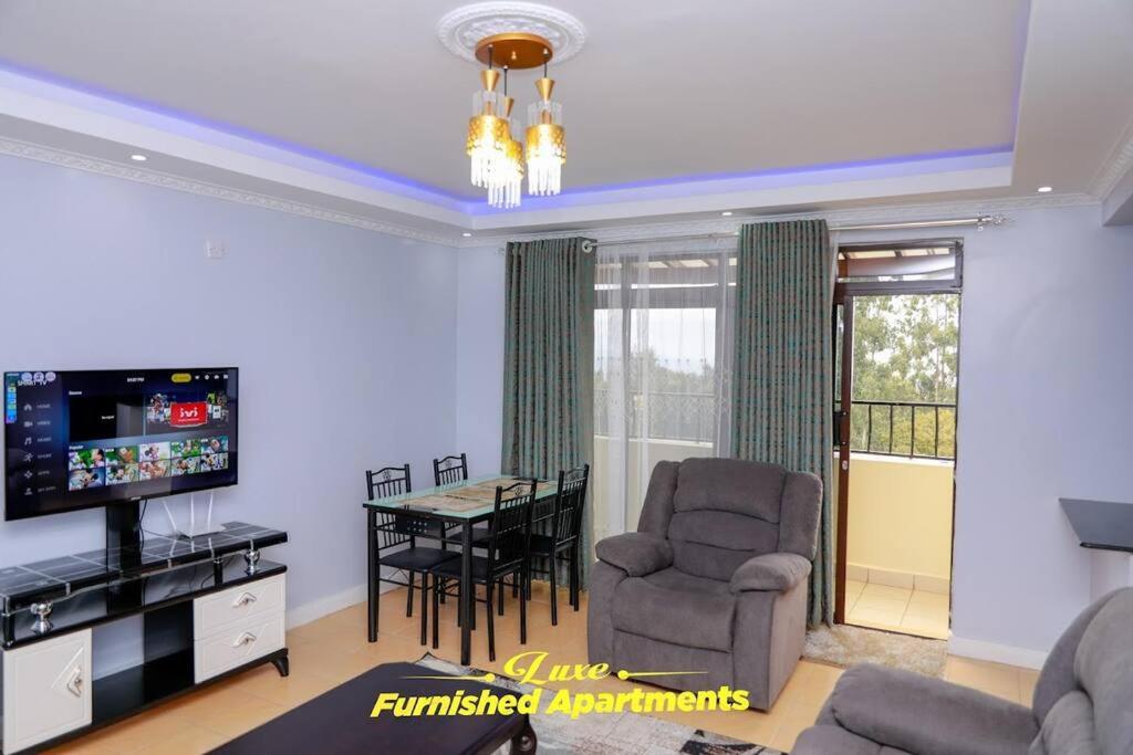 a living room with a television and a dining room at Luxe Furnished Apartments in Meru