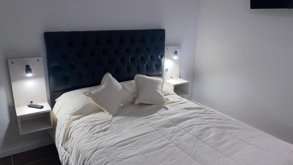 a white bed with two nightstands and two lamps at Altos San Martín in Concepción del Uruguay