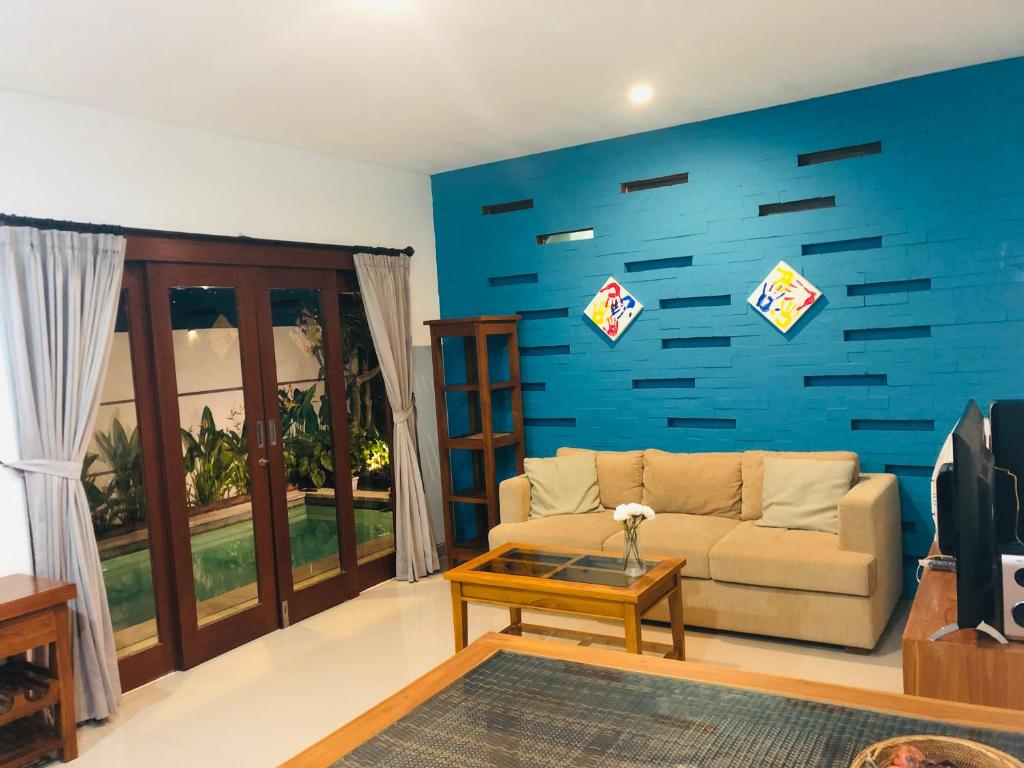 a living room with a couch and a blue wall at Villa Triyuna, our little paradise in Banjar