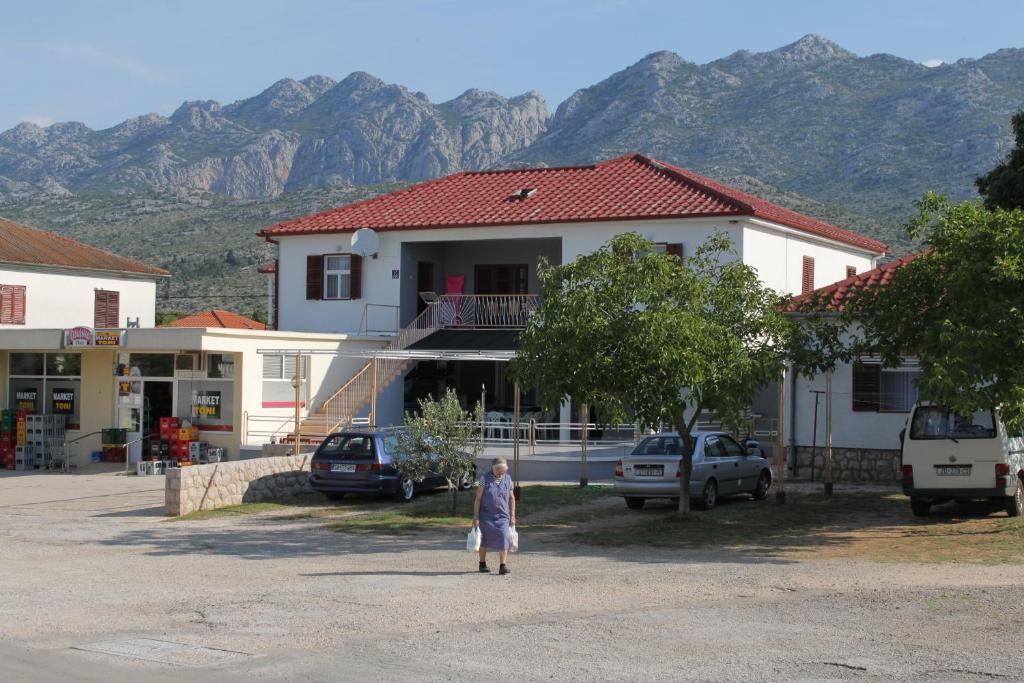 a woman standing in a parking lot in front of a house at Apartments with a parking space Seline, Paklenica - 6628 in Starigrad