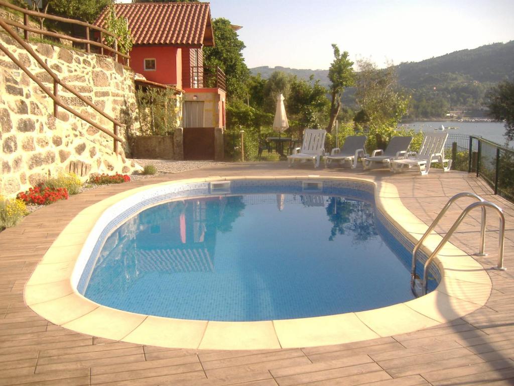 a swimming pool in a patio with chairs and a house at Quinta da Fonte da Poça - Chalé T1 in Geres