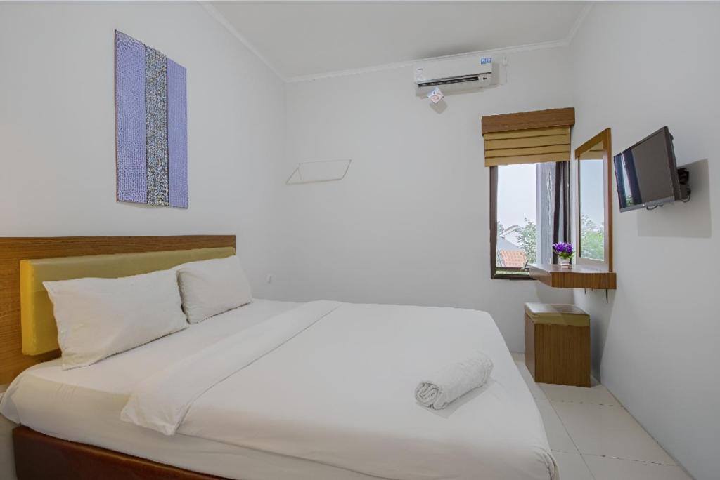 um quarto com uma cama branca e uma janela em Uptown Residence Syariah Pondok Pinang em Jacarta