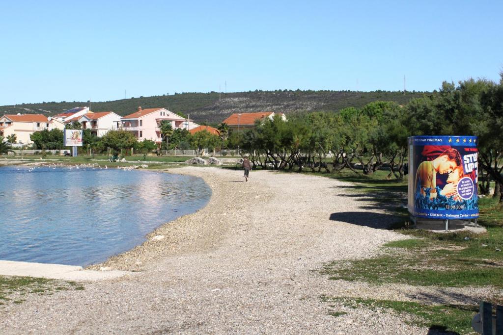 a person walking on a beach next to a body of water at Studio Sukosan 14681a in Sukošan