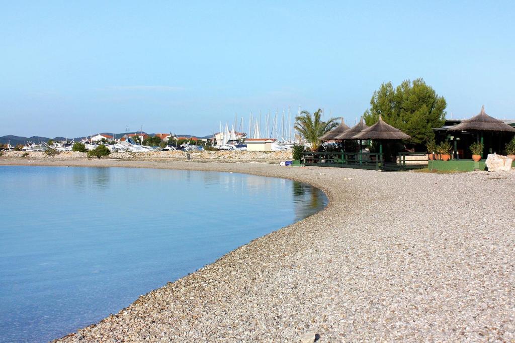 a beach with a body of water and some buildings at Studio Sukosan 14681a in Sukošan