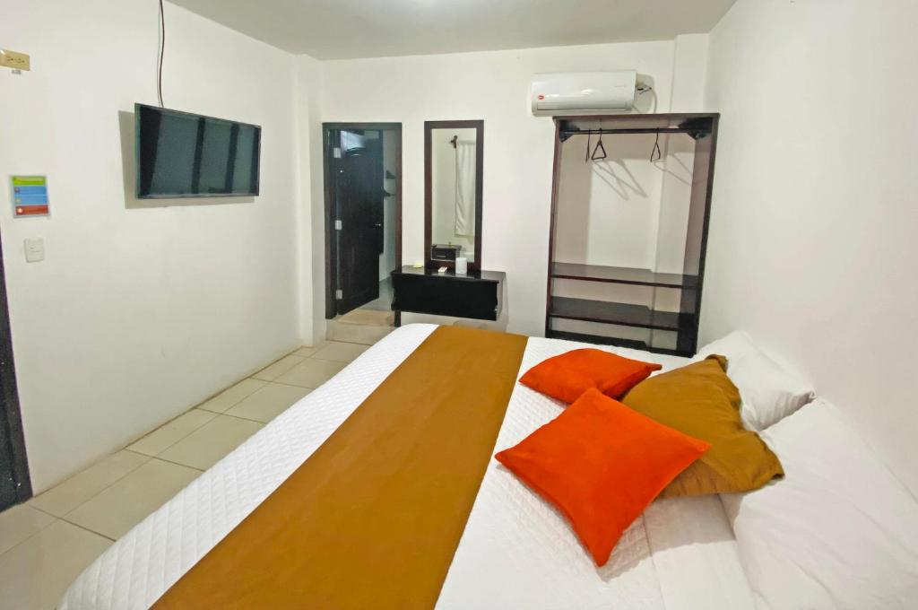 1 dormitorio con 1 cama grande con almohadas de color naranja en Carpao Lodging Galapagos, en Puerto Ayora