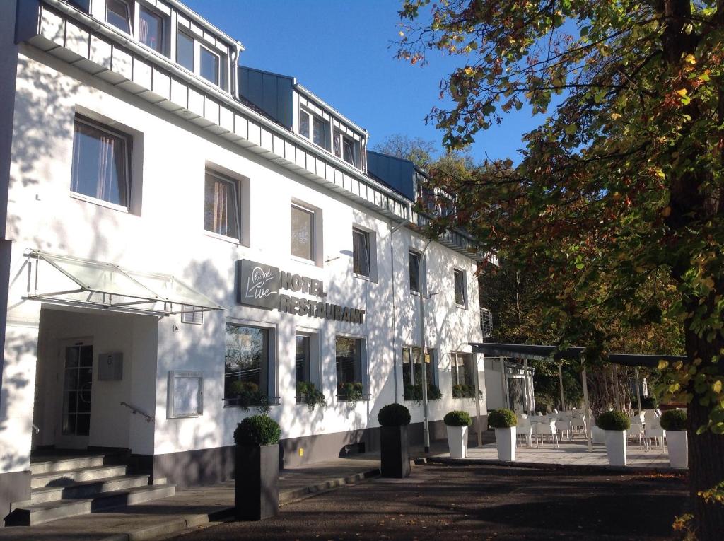 ein weißes Gebäude mit Topfpflanzen davor in der Unterkunft Hotel und Apartment Garni Eurode Live in Herzogenrath