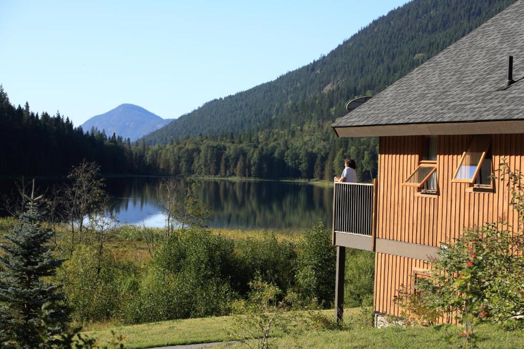 una persona parada en el balcón de una casa con vistas al lago en Alpine Meadows Resort, en Clearwater