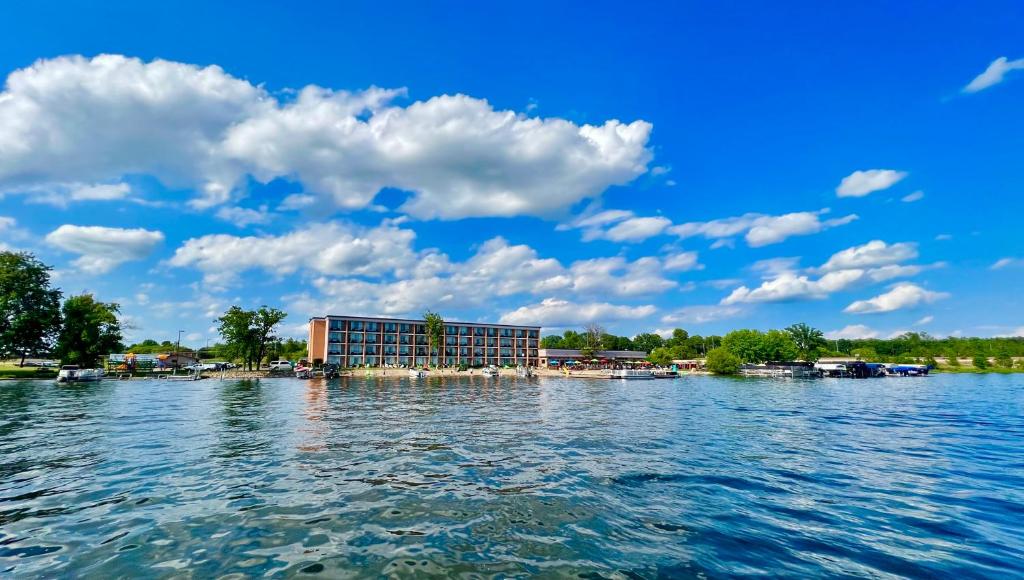 un hotel en un lago con un cielo azul y nubes en Holiday Inn Detroit Lakes, an IHG Hotel, en Detroit Lakes