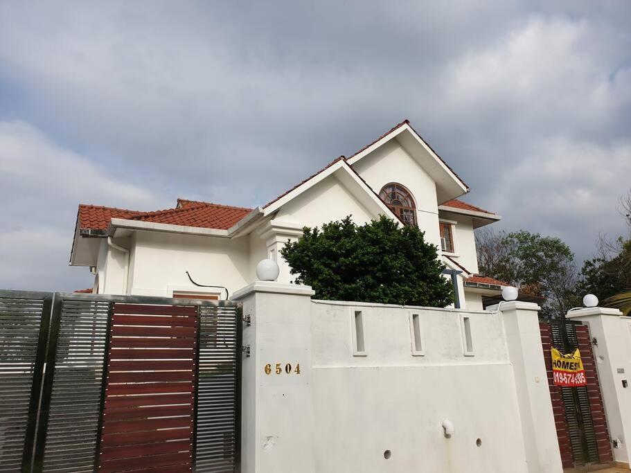 a white house with a gate and a fence at Nilai Spring Villas in Nilai