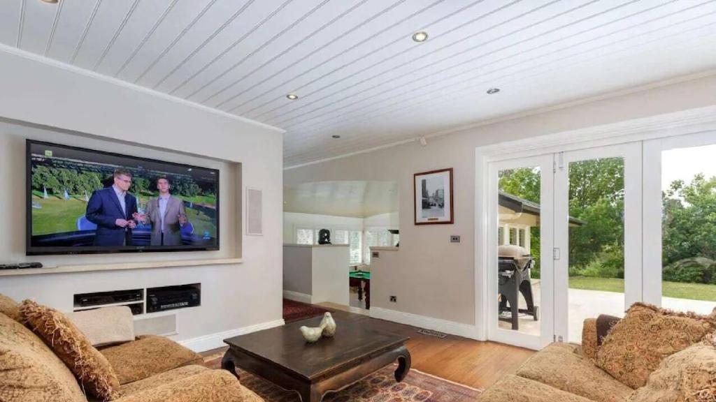 Ellengowan In Leura on 2 acres في ليورا: غرفة معيشة مع تلفزيون بشاشة مسطحة على الحائط