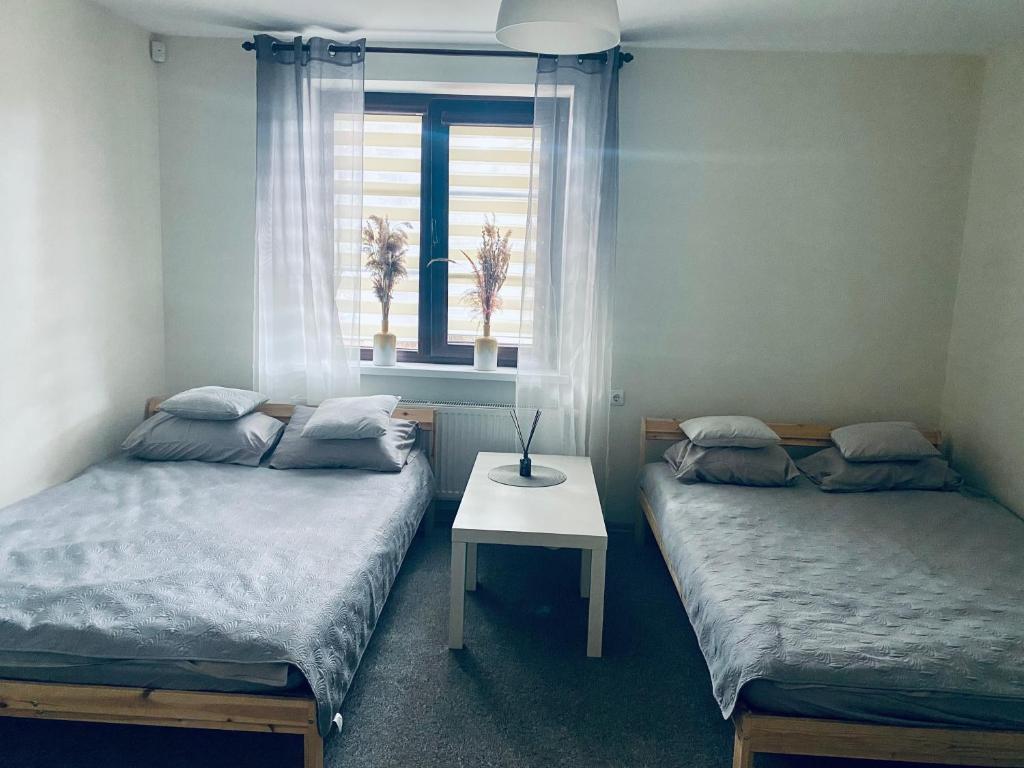 duas camas num quarto com uma janela e uma mesa em Pušų kiemas em Palanga