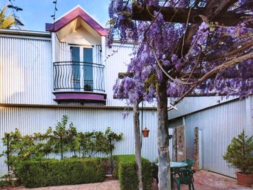 een paarse bloeiende boom voor een wit gebouw bij The Stable On Olive in Mildura
