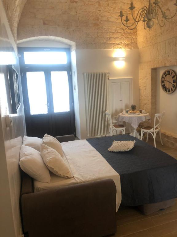 ein Schlafzimmer mit einem Bett, einem Tisch und einer Uhr in der Unterkunft Nido di pietra-dimora in centro in Alberobello
