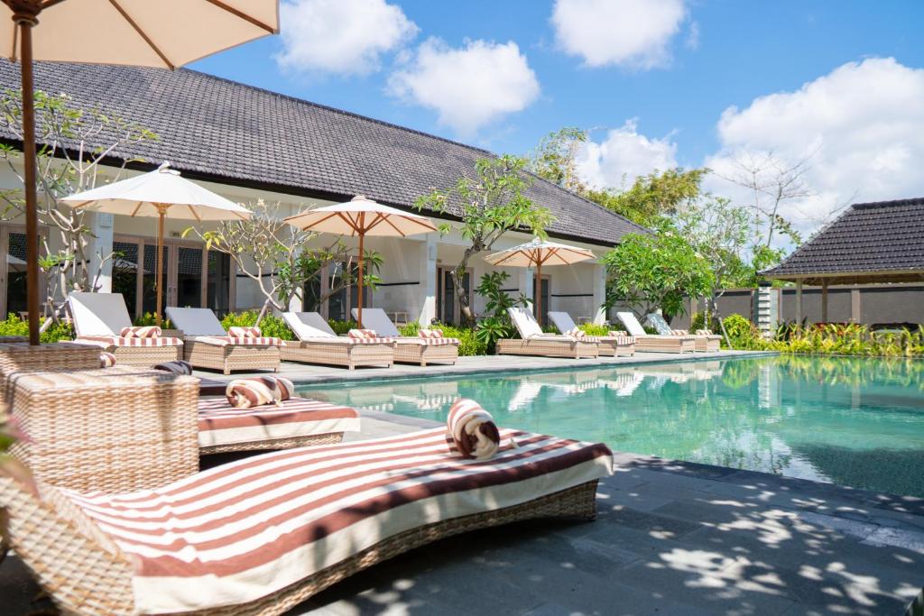 an image of a swimming pool with chairs and umbrellas at Green D'Mel Luxury Homestay in Nusa Dua