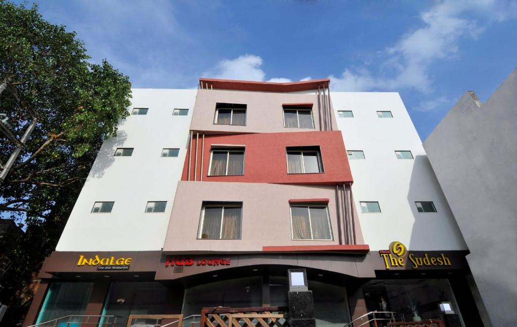 a tall white building with a red at Hotel The Sudesh in Raipur