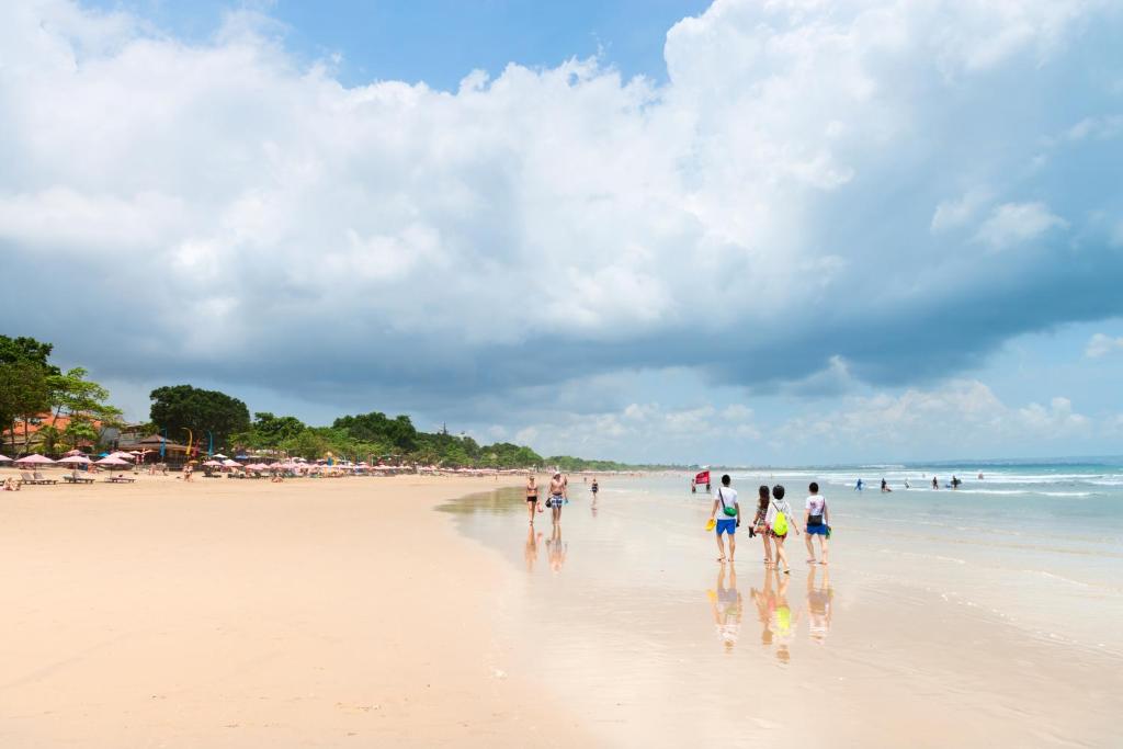 un gruppo di persone che camminano sulla spiaggia di Seminyak Villa a Seminyak