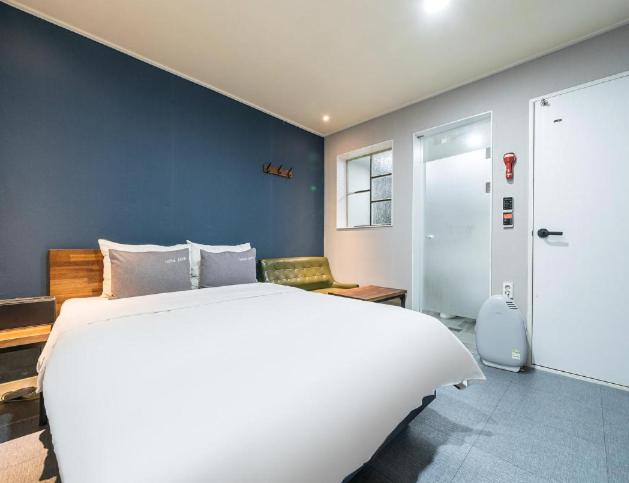 光阳Java Hotel的卧室配有白色的床和蓝色的墙壁