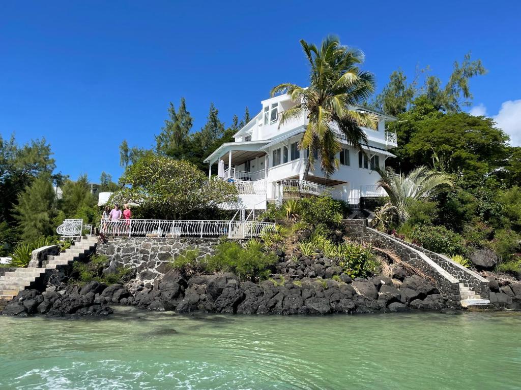 Biały dom na skalistej wyspie w wodzie w obiekcie BEACH VILLA ROCCA w mieście Grand Gaube