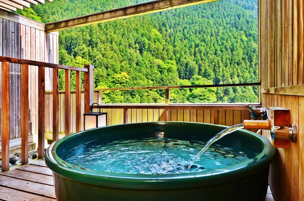 a hot tub on a deck with a view of the mountains at Sunriver Oboke in Miyoshi