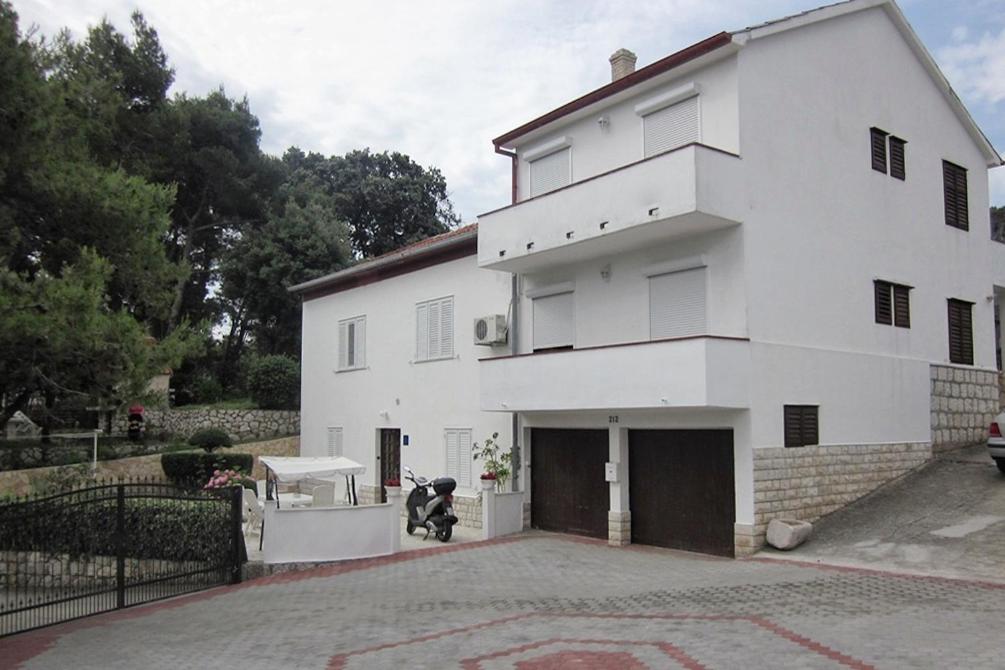 a white house with a dog standing in front of it at Apartment Mundanije 5072b in Rab