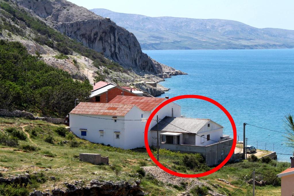 a house on the side of a hill next to the water at Apartment Metajna 6465c in Metajna
