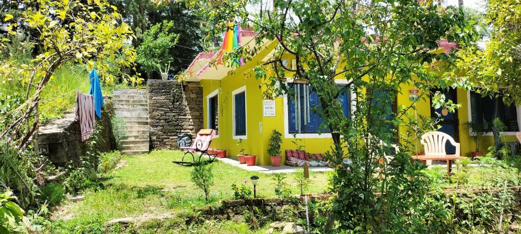 a yellow house with two chairs in the yard at Le Jardin . (The garden) in Almora
