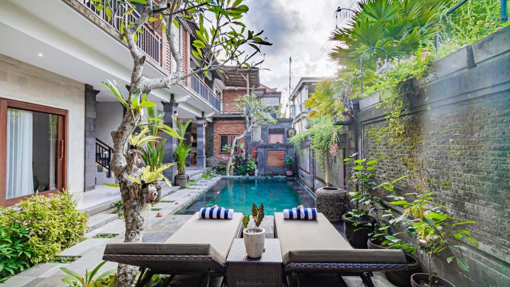 un patio esterno con piscina, tavolo e sedie di Ayu Sari Guesthouse by Mahaputra ad Ubud