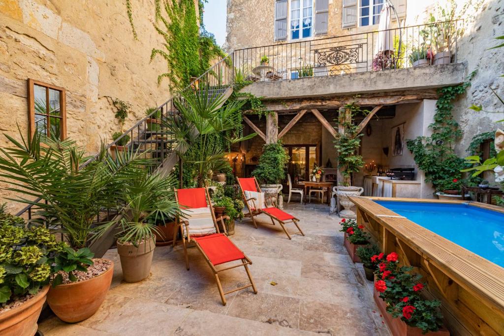 un patio con piscina, sillas y plantas en Luxueuses Suites & Chambres d'hôtes - accueil champagne, petit-déjeuner - Maison Champagne, en Condom