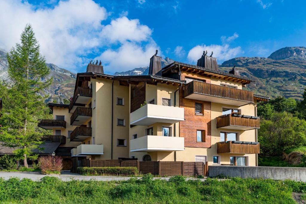 a building with balconies and mountains in the background at Pra d'Sura in Maloja